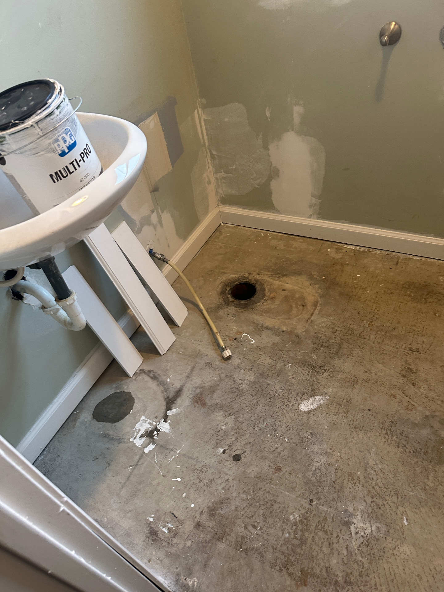 Bare concrete floor next to old shower before flooring install