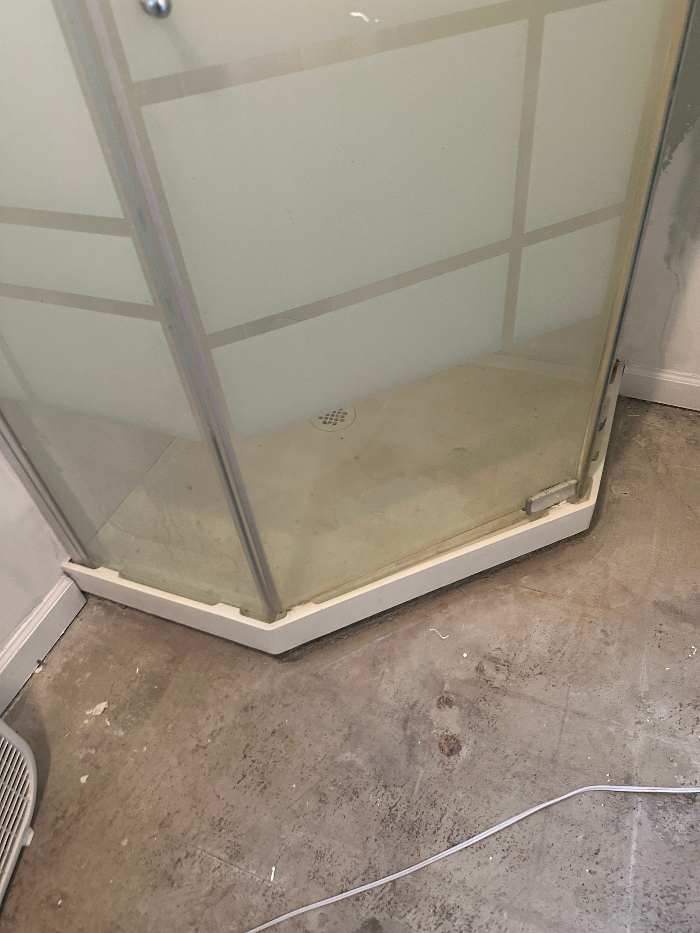 Old shower stall on bare concrete floor before remodel