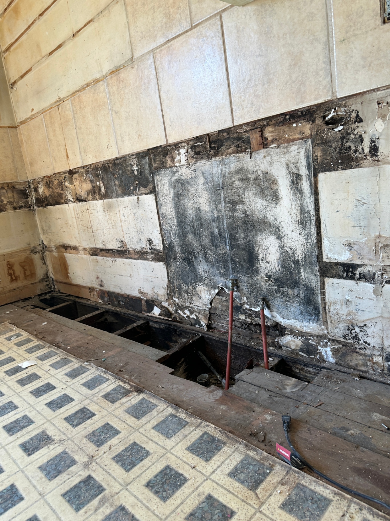 Kitchen with rotted subfloor and water-damaged wall before remodel
